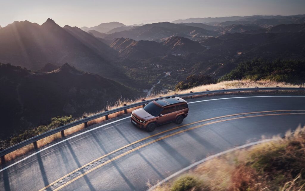 SUV driving a winding mountain road at sunset