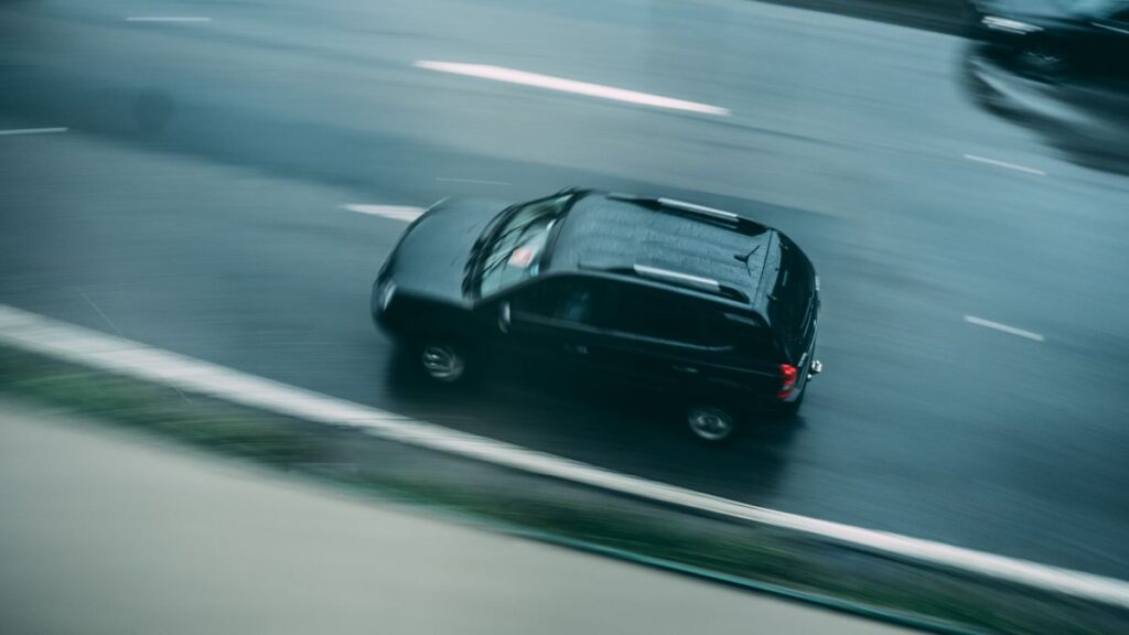 Dark SUV driving along a wet highway in the rain