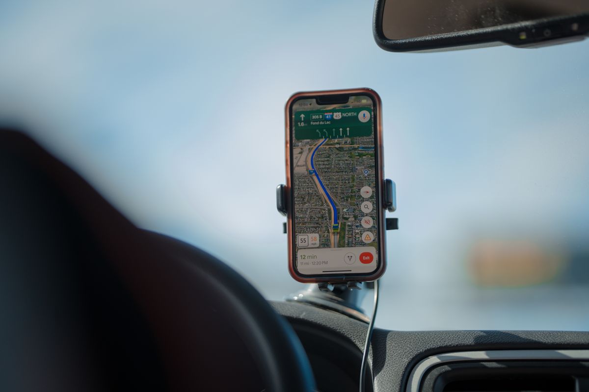 Smartphone in a dashboard mount showing a navigation route while driving
