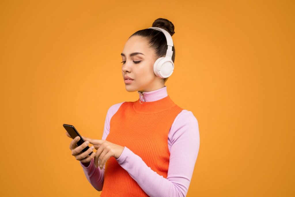 Woman wearing headphones and streaming music on her phone