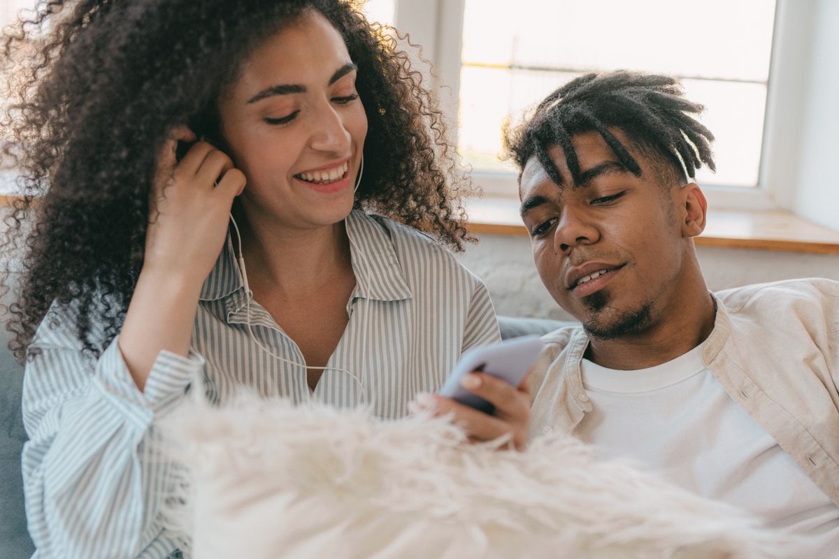 Couple sharing earphones and listening to music together
