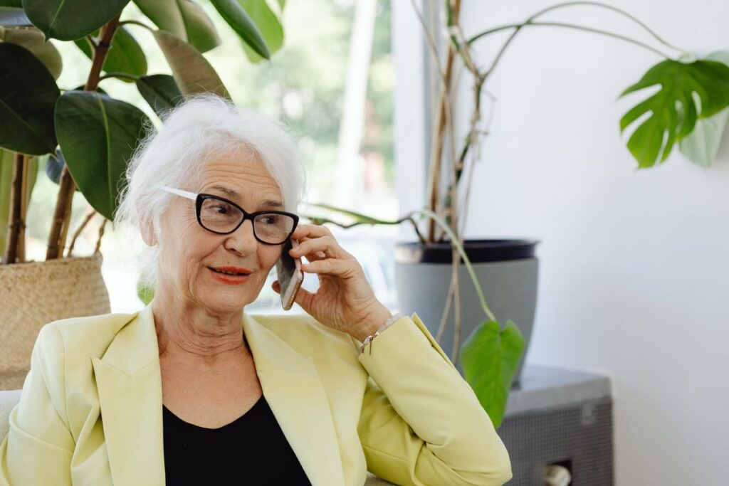 Cell Phone Plans and Home Internet With Monthly Member Savings Older woman in a yellow blazer talking on her phone at home