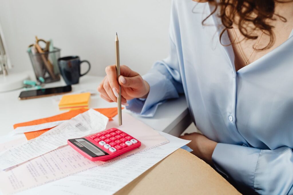 Debt Consolidation Loans That Roll Credit Card Balances Into One Fixed Payment Woman working through bills with a calculator at her desk