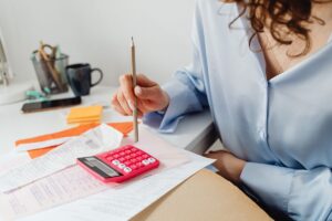 Woman working through bills with a calculator at her desk