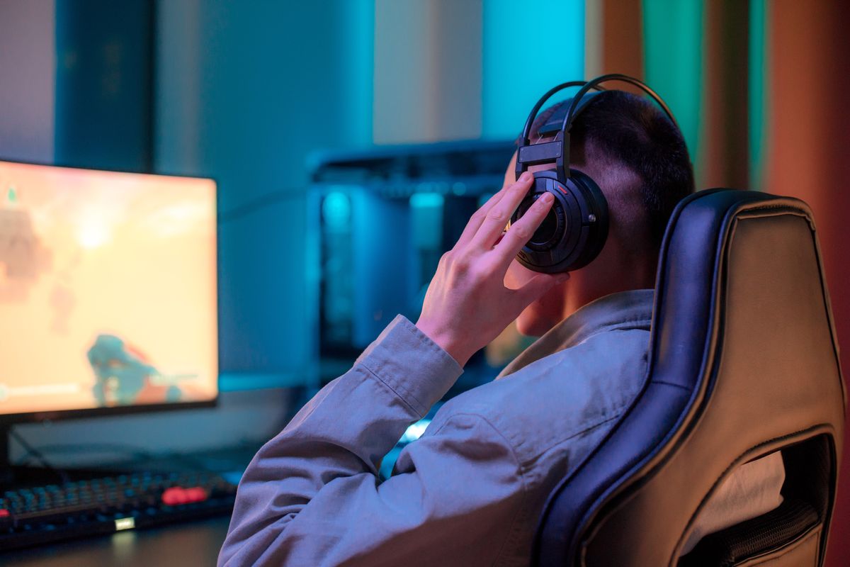 Gamer in a headset sitting in a gaming chair in front of a PC monitor