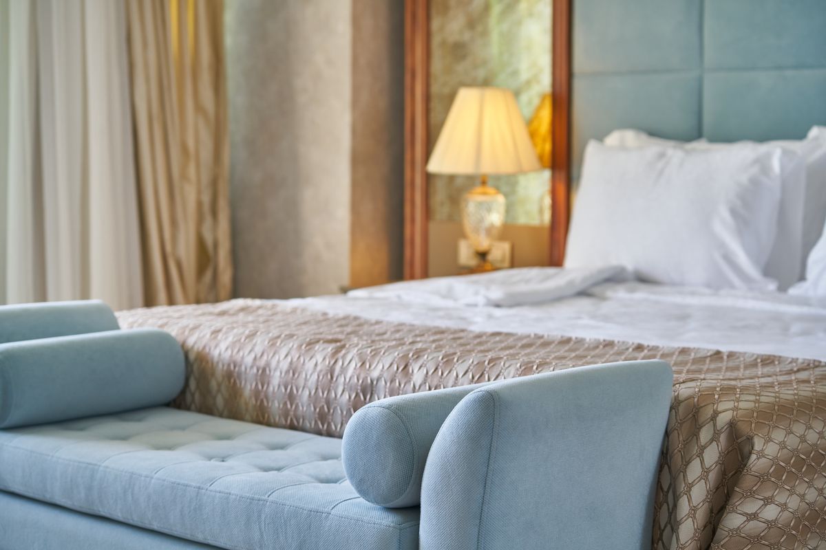 Elegant hotellrom med sofabenk ved fotenden av sengen