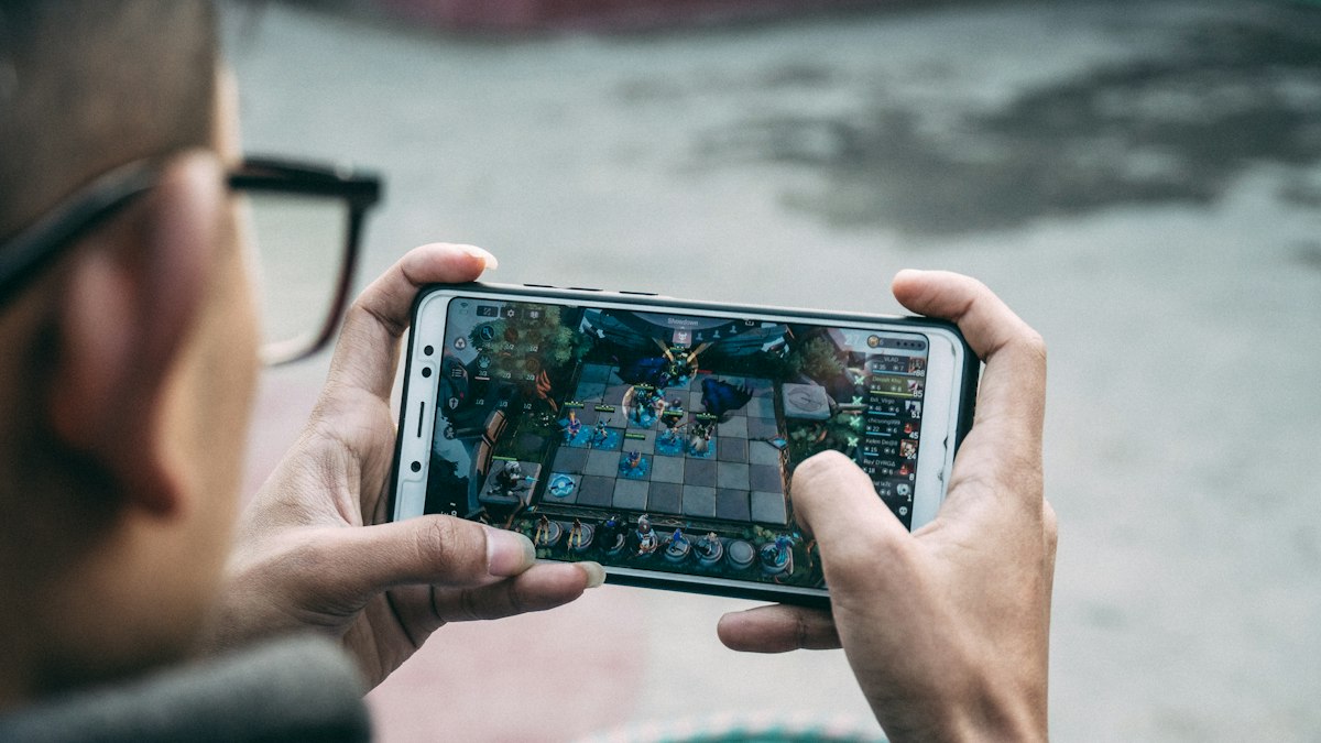 Mann mit Brille spielt ein Strategiespiel auf dem Smartphone
