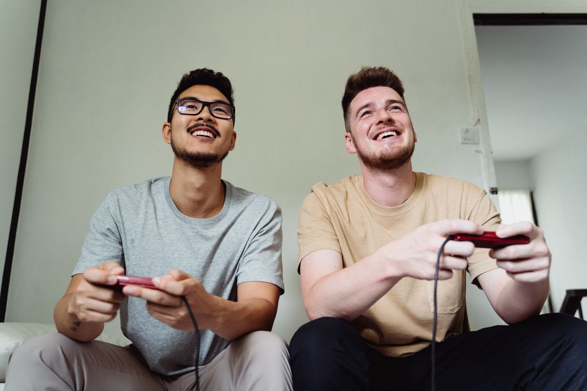 Two friends laughing while playing a console game with controllers