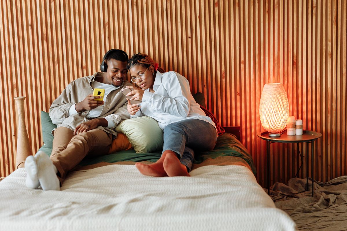 Couple relaxing on a bed listening to music on headphones