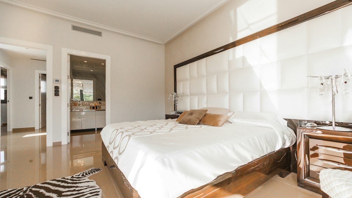 Ljust hotellrum med stor säng och vadderad sänggavel
