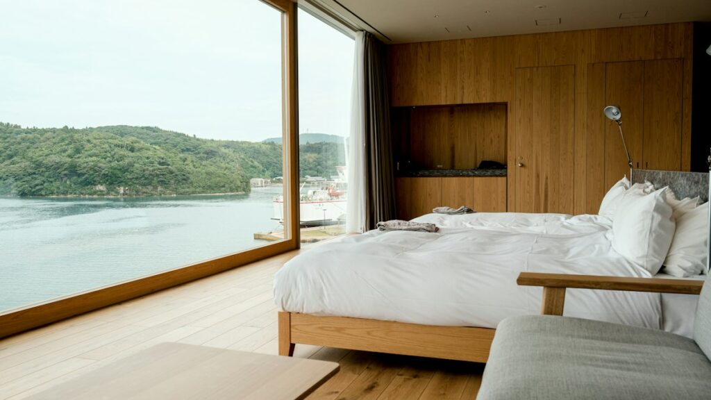 Premium hotel room with a large bed and floor-to-ceiling windows over a harbour