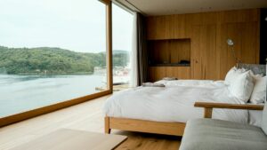 Premium hotel room with a large bed and floor-to-ceiling windows over a harbour