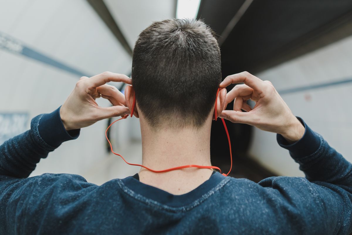 Commuter putting on headphones in an underground station