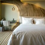 Luksuriøst hotellrom med stor dobbeltseng og skulpturert sengegavl