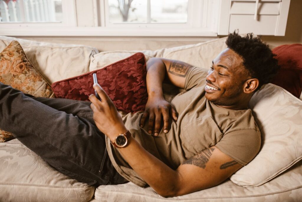 A man relaxing on a sofa using his phone