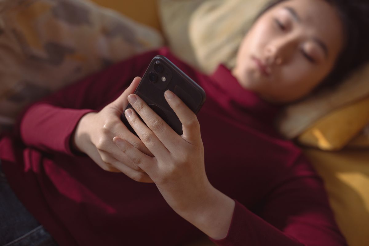 A woman using her phone while lying down