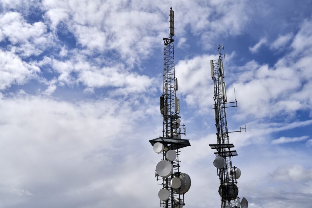 Two mobile network masts against a cloudy sky