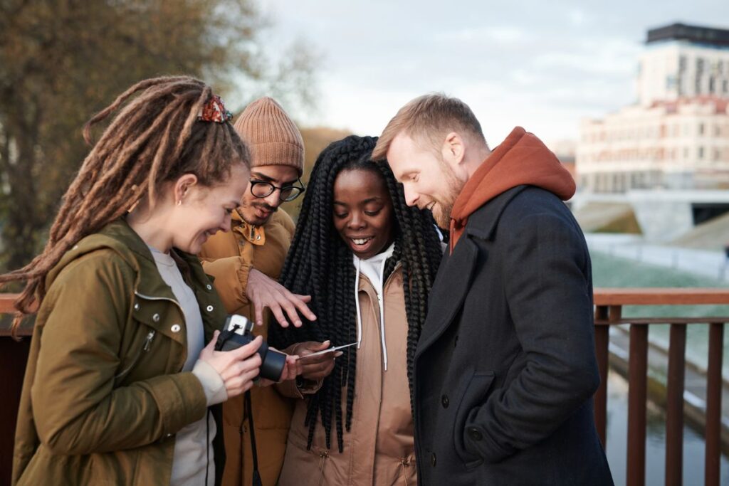 Four friends looking at a phone together outdoors