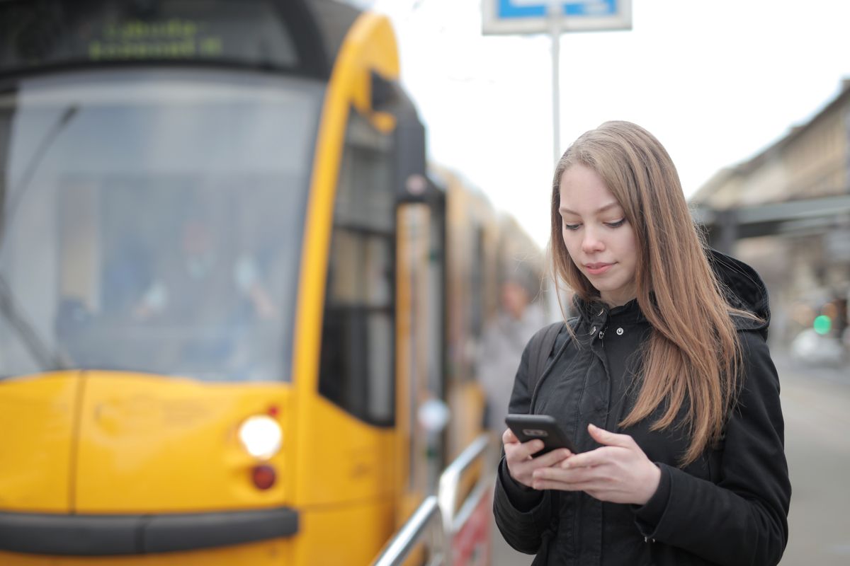A woman using her phone beside a tram