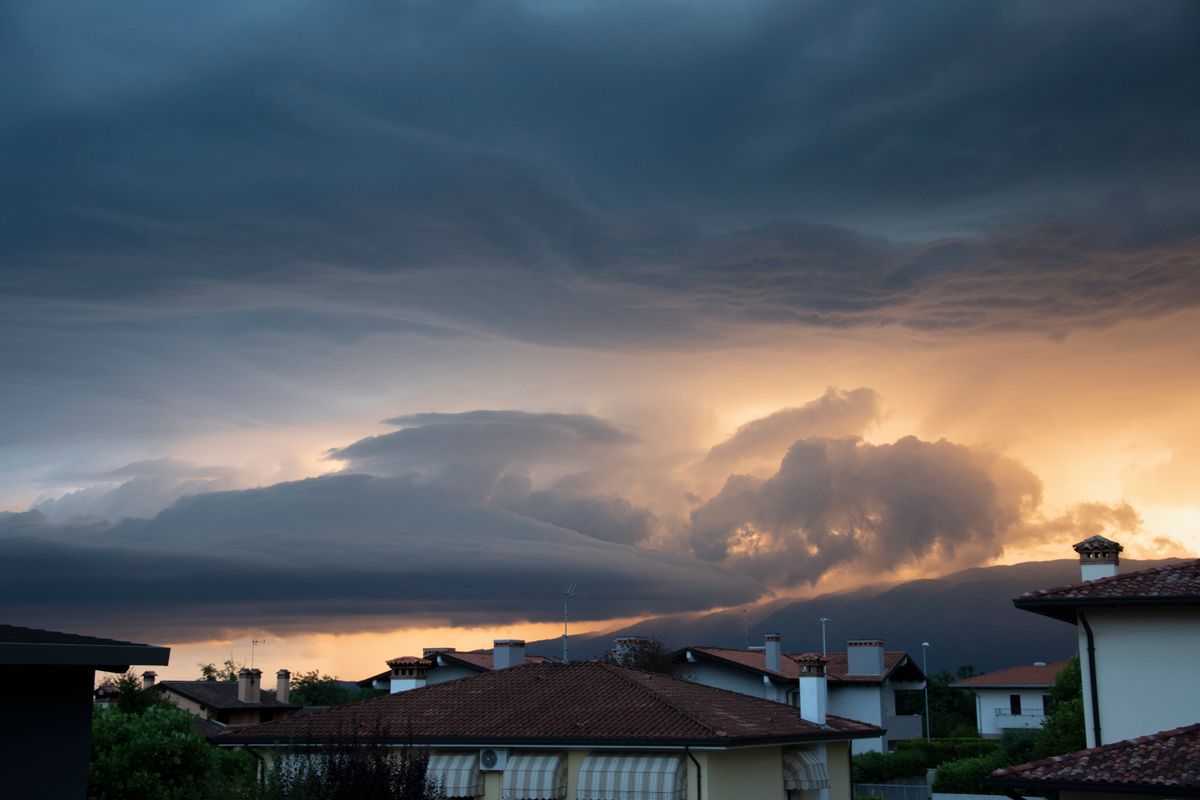 Dark storm clouds gathering over rooftops at sunset