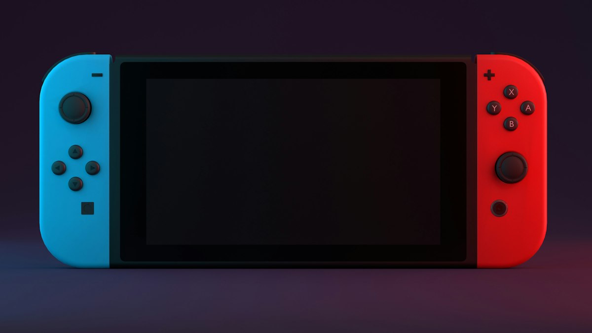 Handheld games console with blue and red controllers on a dark background