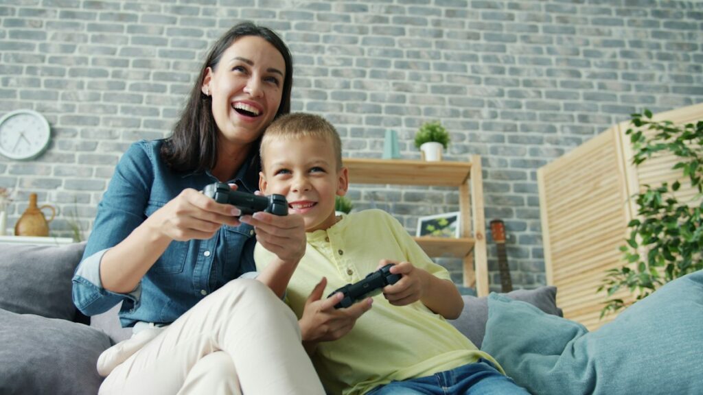 Mutter und Sohn spielen gemeinsam ein Videospiel auf dem Sofa
