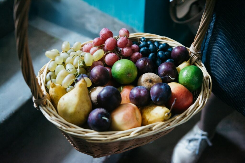 Wicker gift basket filled with fresh grapes, pears and plums
