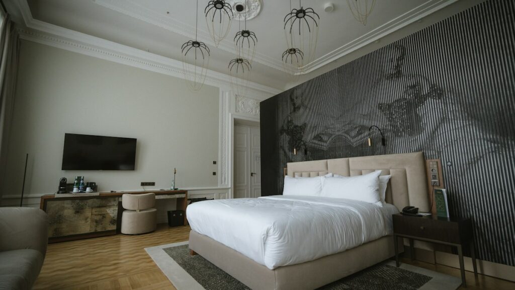 Elegant hotel bedroom with a king bed, patterned feature wall and designer pendant lights