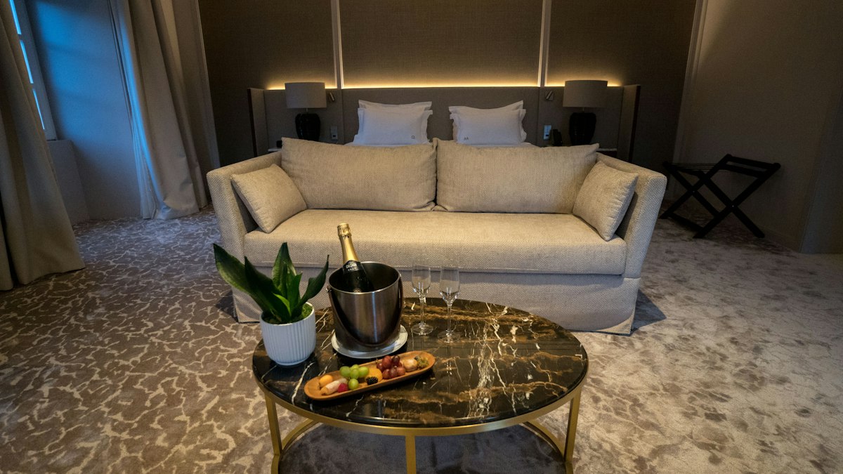 Luxury hotel suite lounge with a sofa, marble table and champagne on ice