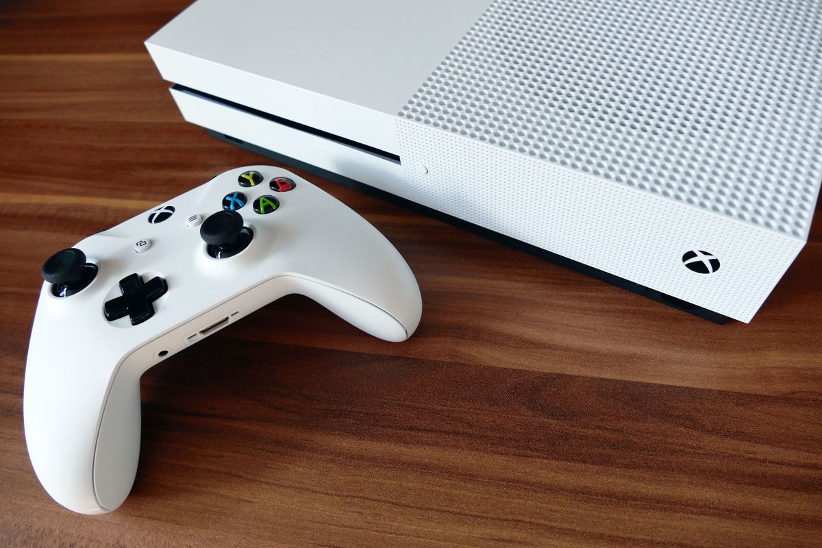 White Xbox console and matching controller on a wooden desk