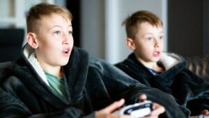 Two boys absorbed in a video game on the sofa