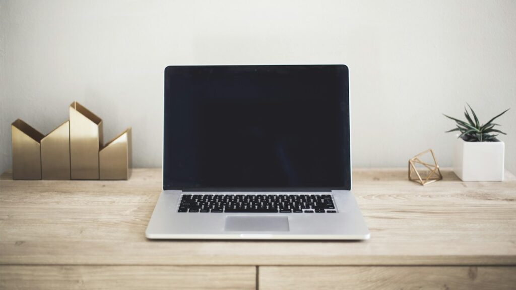 Generalüberholte MacBooks für Studium und Homeoffice Aufgeklapptes Notebook auf einem Holzschreibtisch