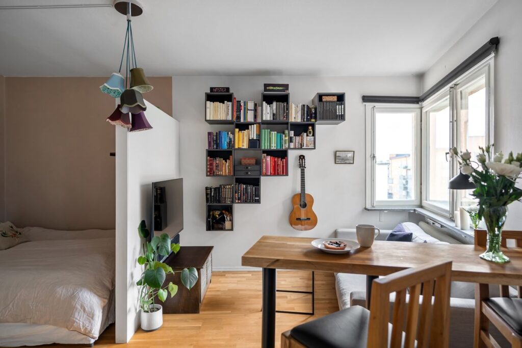 Renters Insurance Coverage for Belongings, Valuables and Earthquake Damage Studio apartment with a bookshelf, guitar, dining table and bed full of everyday belongings