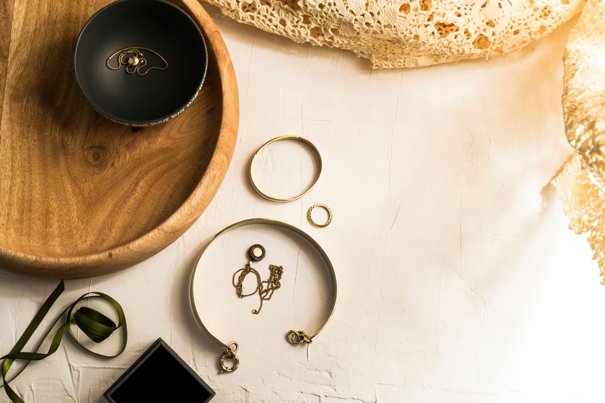 Gold rings, bracelets and earrings laid out on a wooden tray