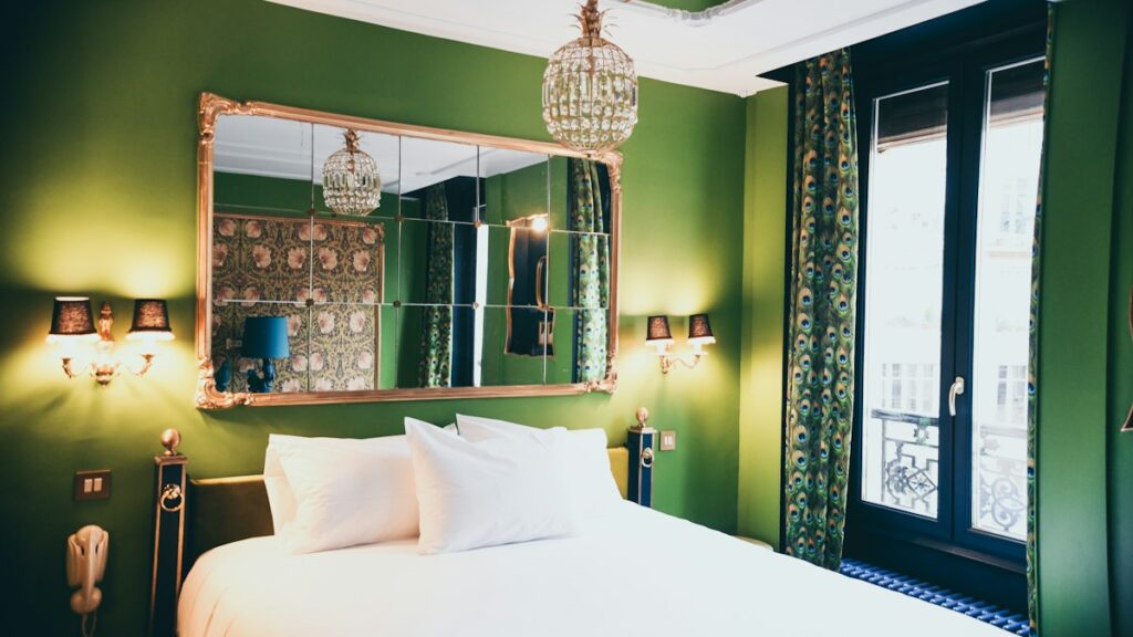 Boutique hotel room with green walls, a chandelier and a gilded mirror