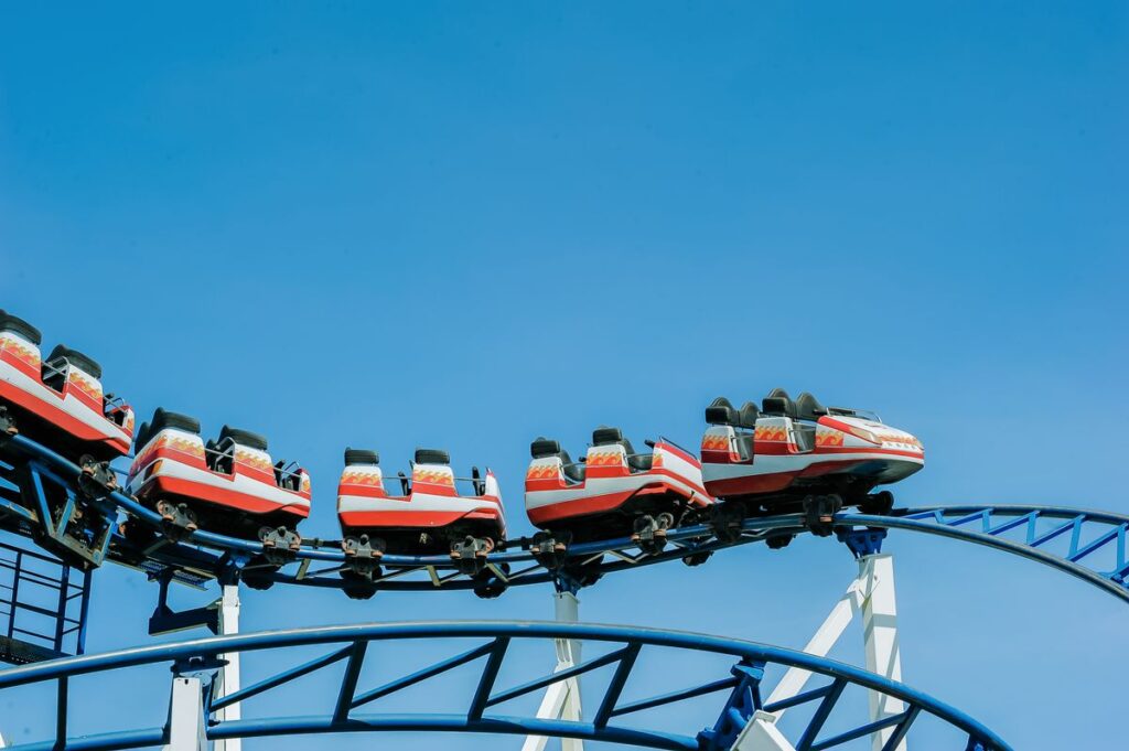 Roller coaster train climbing a blue track against a clear sky
