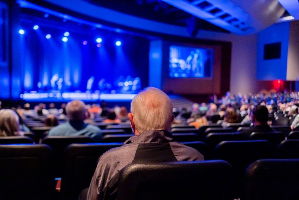 Older man watching a live performance from a theater seat