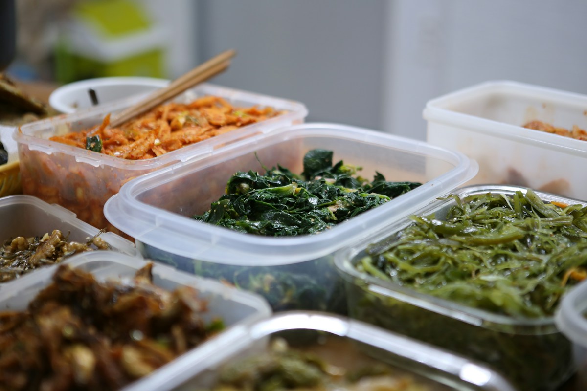 Plastic containers of cooked greens and side dishes ready to be stored
