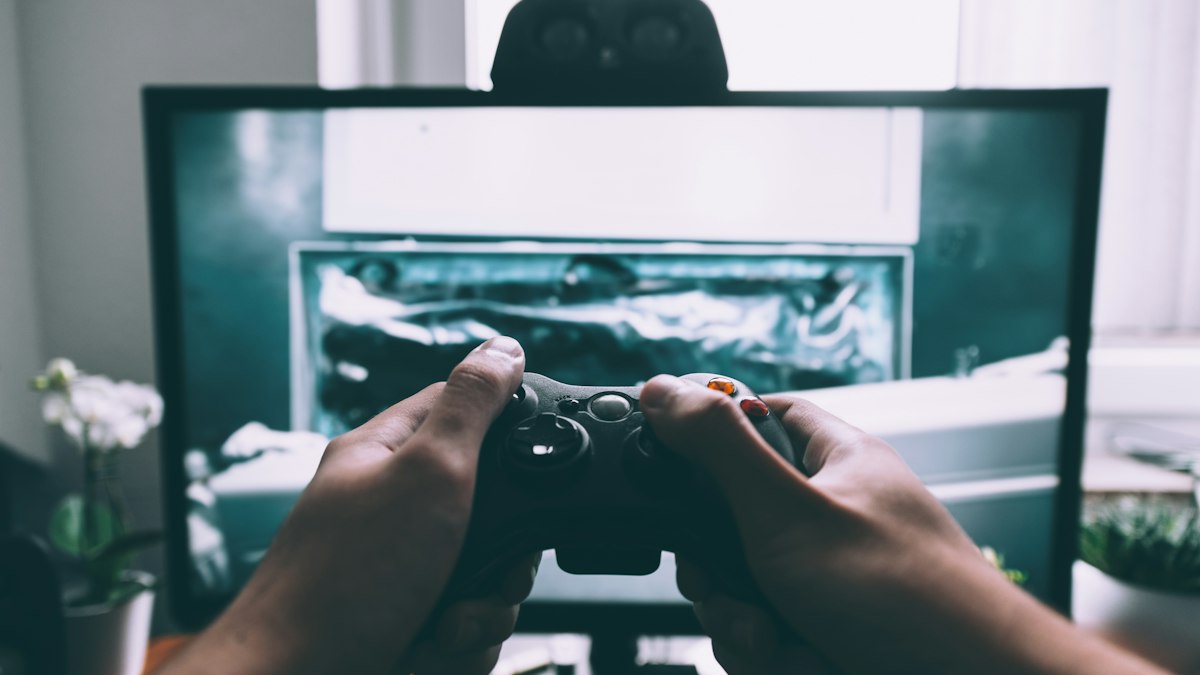 Hands holding a game controller in front of a screen